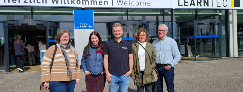 Fünf Personen vor dem Eingang zur LearnTec Messe für digitale Bildung